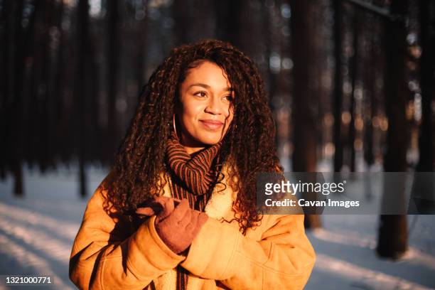 happy young woman looking at sun standing in park during winter - one young woman only health hopeful stock pictures, royalty-free photos & images
