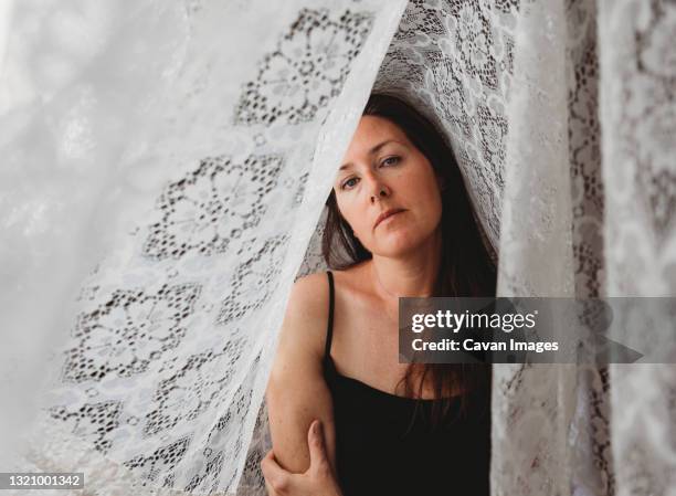 beautiful woman with long brown hair surrounded by lace curtains. - lace shirt stock pictures, royalty-free photos & images