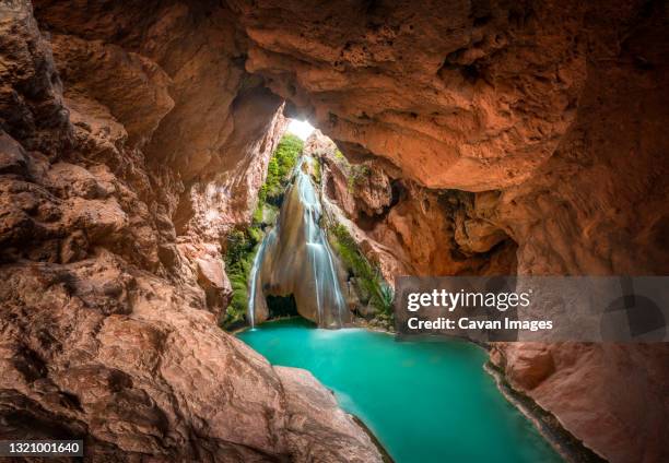 waterfall inside a cave and a lake of crystal clear turquoise water. - crystal caves stock-fotos und bilder