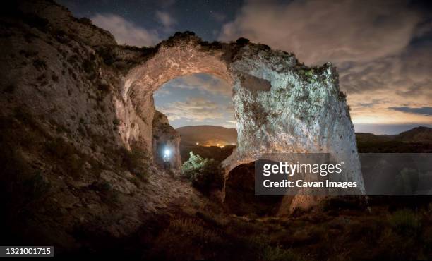the silhouette of a man illuminates two large stone arches - starry vault stock pictures, royalty-free photos & images