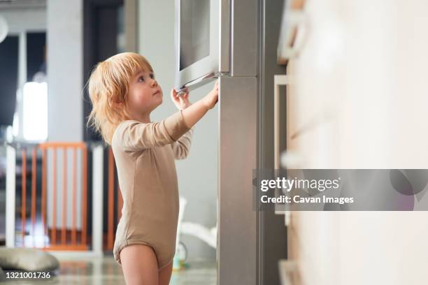 ginger boy looks into the fridge - de petite taille stockfoto's en -beelden