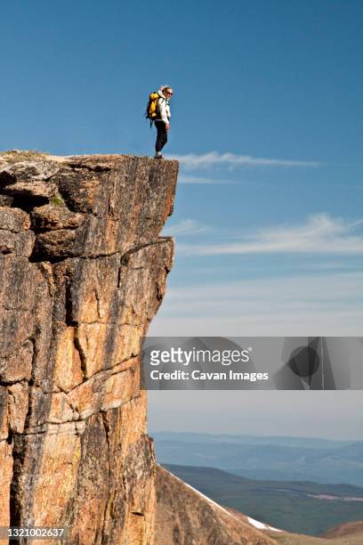active and fit female backpacker standing on the edge of a cliff - falésia - fotografias e filmes do acervo