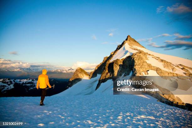 mountaineer holding ice axe approaches mountain summit. - aproximar imagens e fotografias de stock