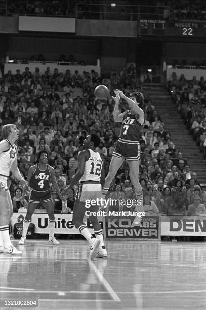 New Orleans Jazz forward guard Pete Maravich passes the ball over Nuggets players Ted McClain and Dan Issel as Jazz guard Freddie Boyd watches the...