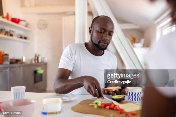 young man making sandwich for breakfast - een broodje smeren stockfoto's en -beelden