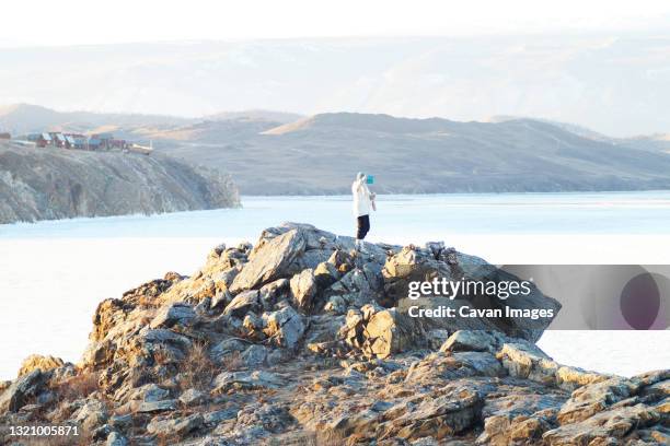 the woman on the rock catches the connection on the phone - irkutsk photos et images de collection