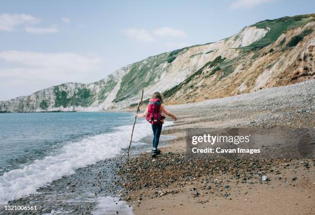 girl walking along the jurassic coast with a stick on a beautiful day - jurassic coast world heritage site stock pictures, royalty-free photos & images