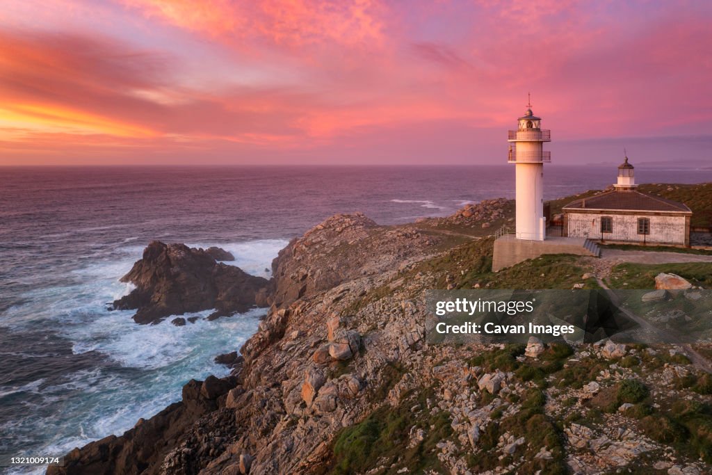 Cape Tourinan Lighthouse drone view at sunset with pink clouds, Spain