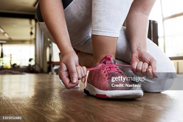 unrecognizable young female athlete tying her laces while working out in the gym - lace fastener stock pictures, royalty-free photos & images