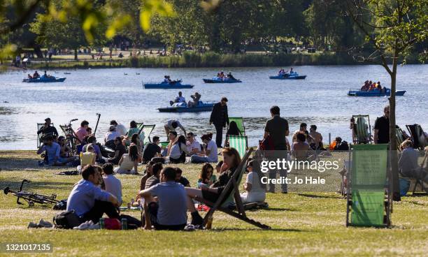 Crowds of people enjoy the sun by the lake in Regents Park on May 31, 2021 in London, England.