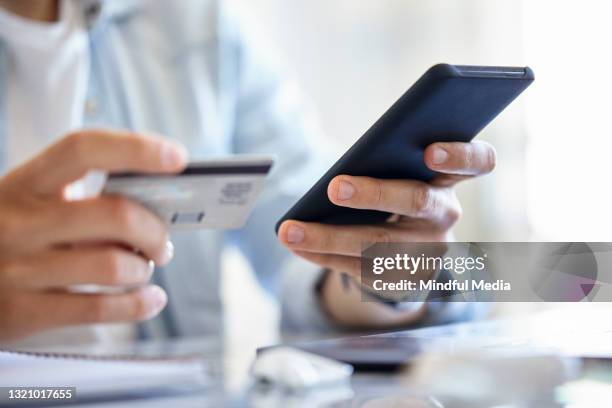 close up of young male designer holding credit card while purchasing online using smartphone during daytime - easy solutions stock pictures, royalty-free photos & images