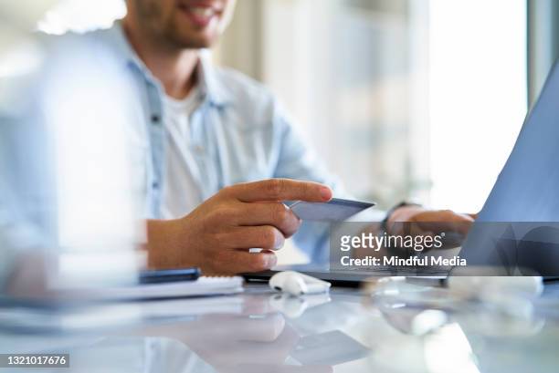 mid section of male freelance worker holding credit card while doing online shopping during daytime - easy solutions stock pictures, royalty-free photos & images