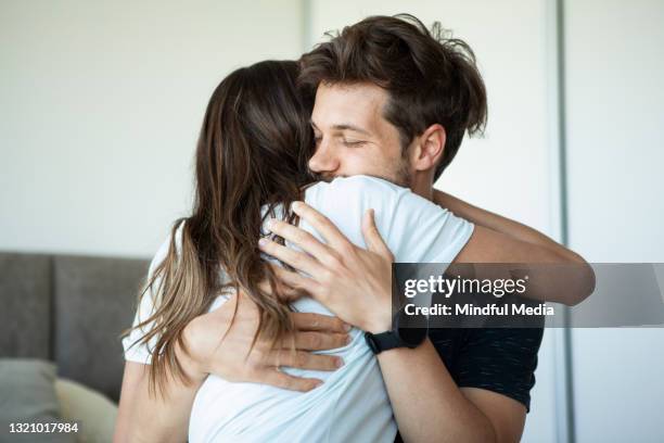 smiling young couple embracing in bedroom - miscarriage stock pictures, royalty-free photos & images