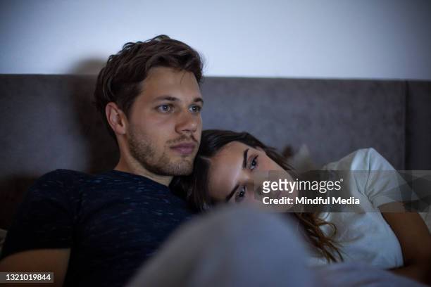 retrato de una pareja cansada acostada en la cama mientras ve la televisión en el dormitorio - lovers 2020 film fotografías e imágenes de stock