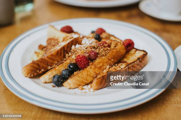 french toast with red berries on a white plate - pain perdu ストックフォトと画像