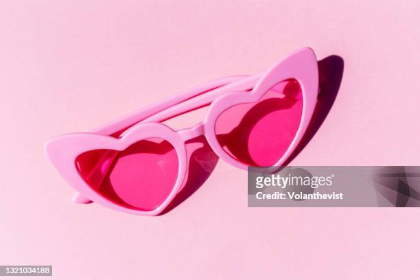 pattern of pink heart-shaped retro sunglasses against pastel pink background - sunglasses photos et images de collection