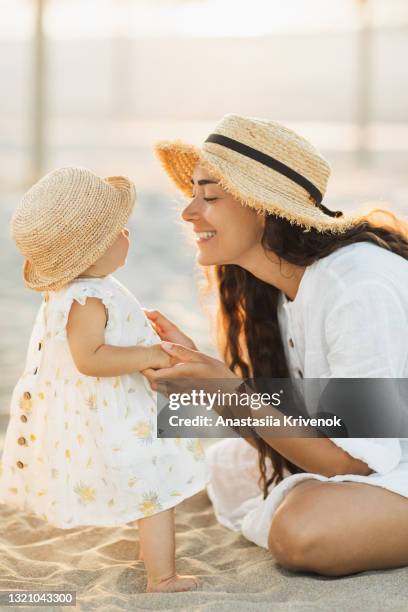 picture perfect mother daughter moment on the beach, gently touching and holding hands - baby lachen natur stock-fotos und bilder