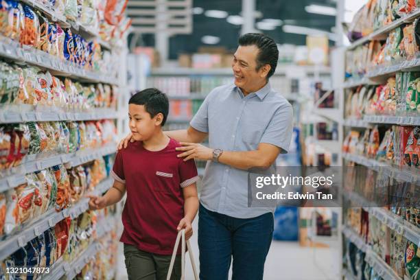 mid volwassen maleisische vader en zoon dragen herbruikbare boodschappentas winkelen in snack sectie supermarkt tijdens het weekend - malaysia father and son stockfoto's en -beelden