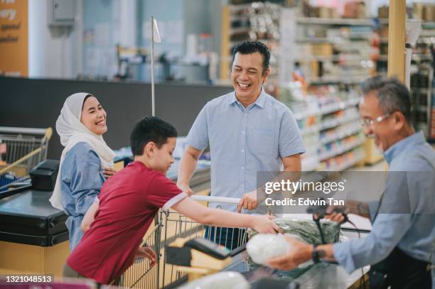 asiatische malay familie mit einem kind check-out im supermarkt kassierer kauf milchprodukte und gemüse - malay hijab stock-fotos und bilder
