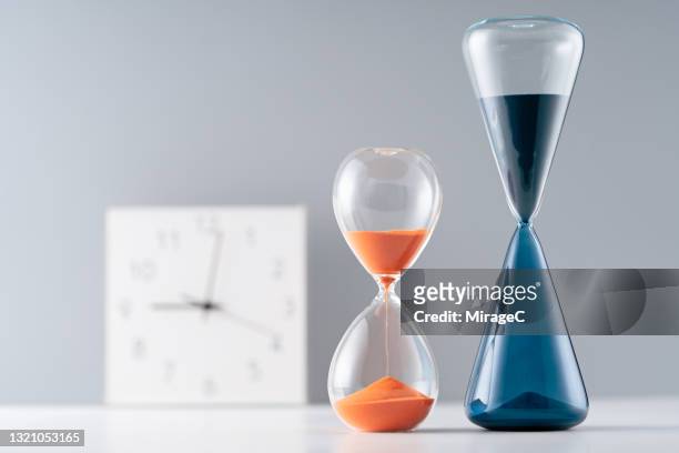 time clock and sand hourglasses - primo turno foto e immagini stock
