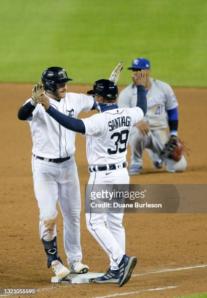 Robbie Grossman of the Detroit Tigers celebrates with first base coach Ramon Santiago, with first baseman Carlos Santana of the Kansas City Royals...