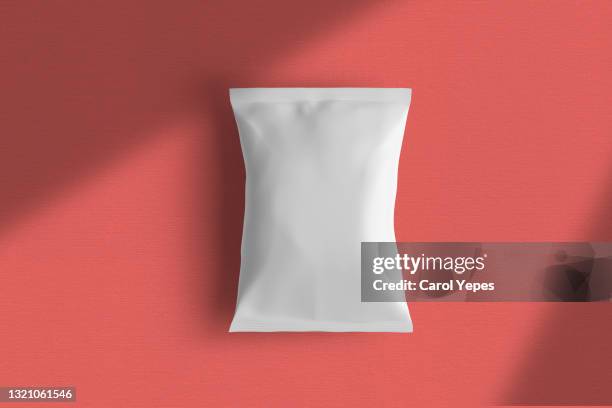blank plastic package mockup/template in red solid background - papier tüte stock-fotos und bilder
