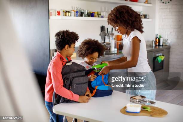 mother making school lunch - packing kids backpack stockfoto's en -beelden