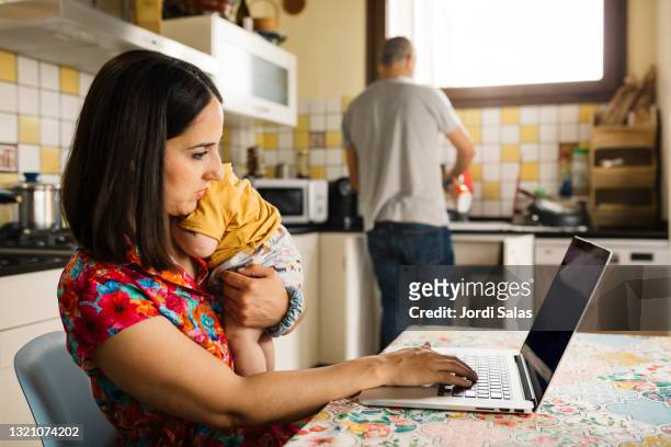 woman with baby working in a kitchen - mother and baby and laptop stock pictures, royalty-free photos & images