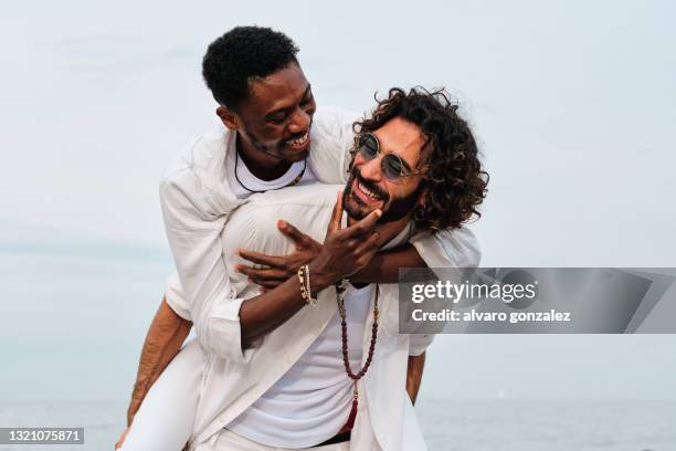 young interracial gay couple playing at the beach - travel destinations diversity stock pictures, royalty-free photos & images