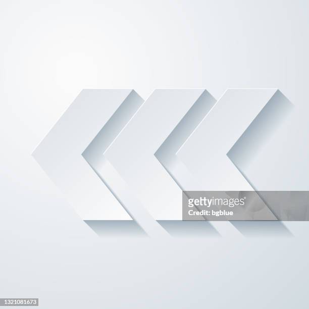 triple chevrons pointing left. icon with paper cut effect on blank background - three dimensional arrow stock illustrations