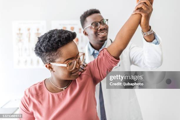 man physiotherapy professional giving a treatment to an attractive female client in a bright medical office - chiropractic stock pictures, royalty-free photos & images