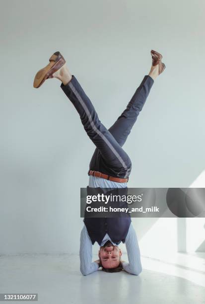 portrait of a smiling man in a shirt and waistcoat doing a headstand - yoga headstand pose imagens e fotografias de stock