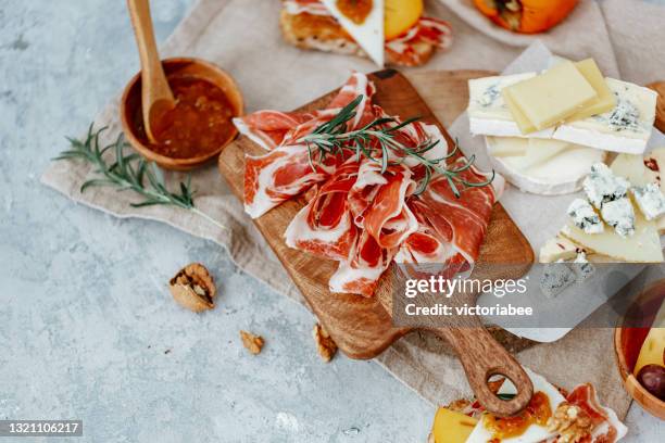 overhead view of serrano ham, cheese board, chutney and toast - tabla de cortar fotografías e imágenes de stock