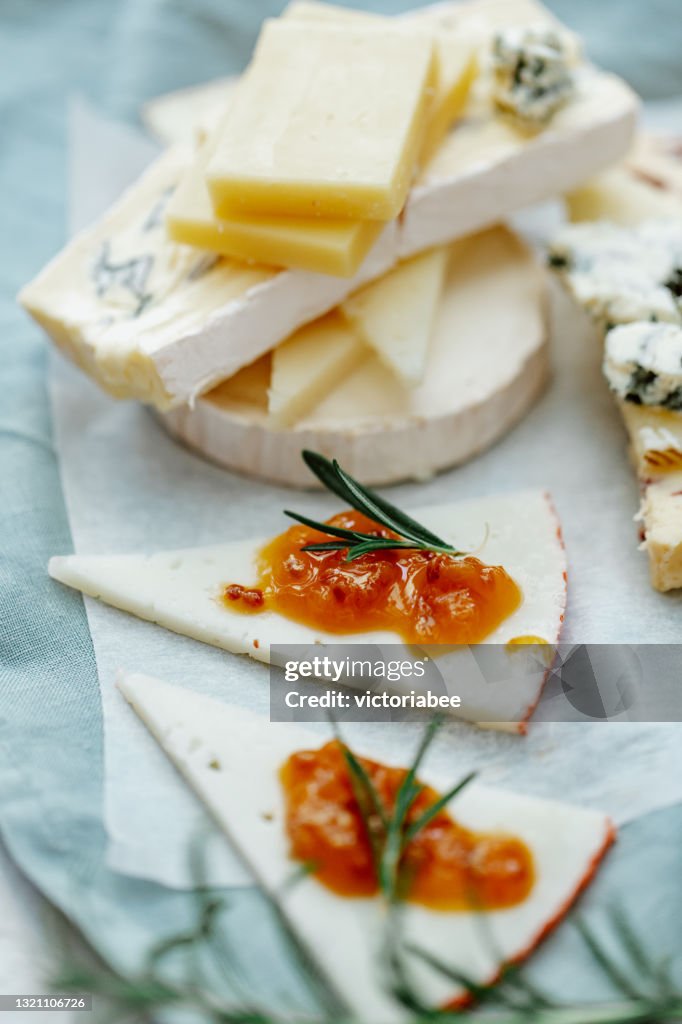 Close-up of a cheese board with a stack of blue cheese, cheddar, goats cheese and chutney