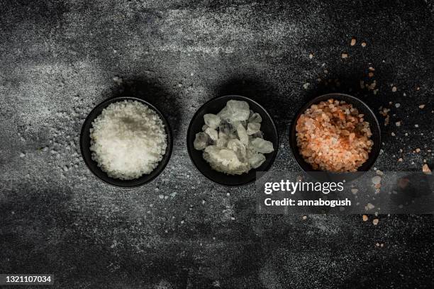 overhead view of three bowls of assorted rock salt on a table - rock salt stockfoto's en -beelden