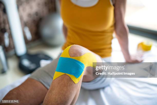 unrecognizable senior patient with kinesio tape on knee, physiotherapy. - kinesiotape stock pictures, royalty-free photos & images