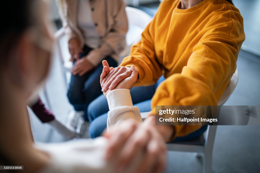 Unrecognizable depressed woman on group therapy, counselling concept.