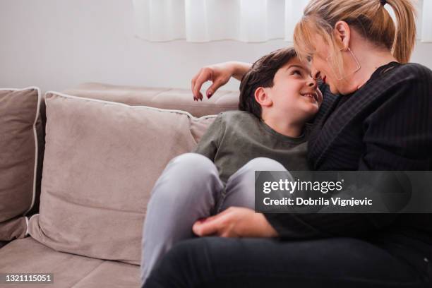 happy young boy cuddling with his mom at home - foster stock pictures, royalty-free photos & images