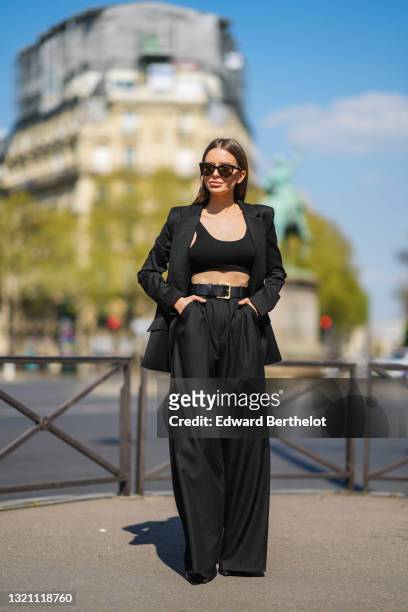 Diana Batovkina wears black Chanel sunglasses, a black Zara tank crop top, a black Zara oversized blazer jacket, a black shiny leather belt, black...