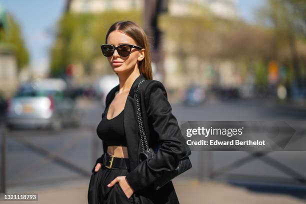 Diana Batovkina wears black Chanel sunglasses, a black Zara tank crop top, a black Zara oversized blazer jacket, a black shiny leather belt, black...