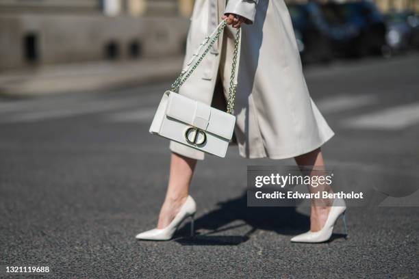 Diana Batovkina wears a white matte leather belted Adriano Baroni trench coat, white leather pointed heels pumps, a white matte 30 Montaigne...