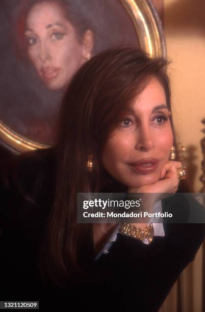 Daniela Zuccoli, wife of Italian TV presenter Mike Bongiorno, posing in her home next to a self-portrait of her. Milan , year 1996