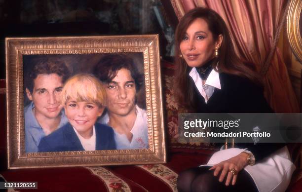 Daniela Zuccoli, wife of Italian TV presenter Mike Bongiorno, posing in her home next to a portrait of her three children. Milan , year 1996