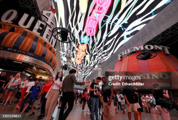 Visitors walk by the Four Queens Hotel & Casino and the Fremont Hotel & Casino under the Viva Vision canopy attraction at the Fremont Street...