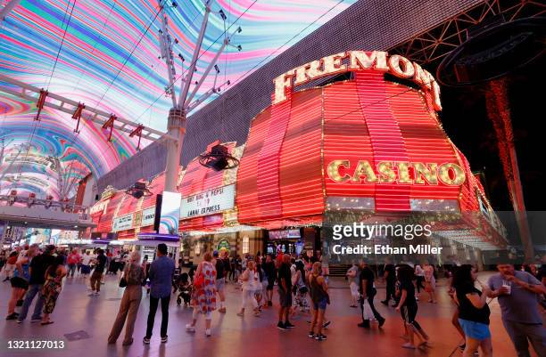 Visitors walk by the Fremont Hotel & Casino under the Viva Vision canopy attraction at the Fremont Street Experience on May 31, 2021 in Las Vegas,...