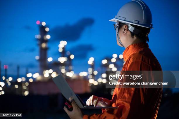 petrochemical engineers work heavily with smart tablets in the oil and gas industry at night. - gas storage stockfoto's en -beelden