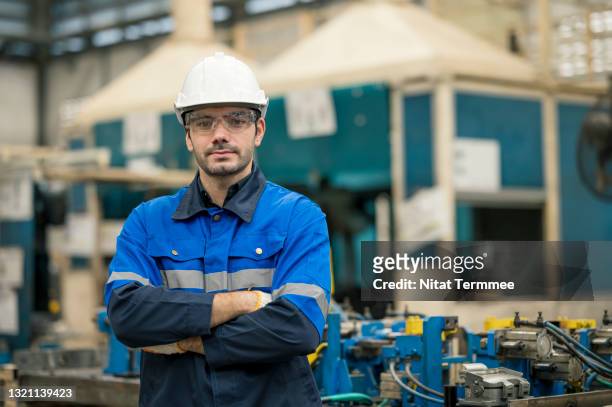 portrait of male production control engineer standing with his arms crossed at production line shop floor. he expert in production planing and improve productivity in a automobile industry. - regular man stock pictures, royalty-free photos & images