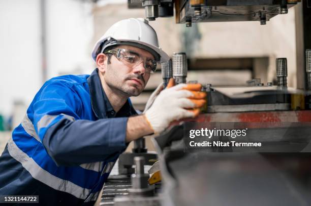 auto part production in automobile industry. production line worker working at large hydraulic stamping press machine. he is preparation tool and dies of auto part production process. - hydraulics stock pictures, royalty-free photos & images