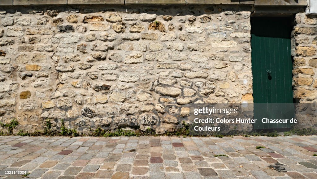 Rustic green door and stone wall and sidewalk in Montmartre