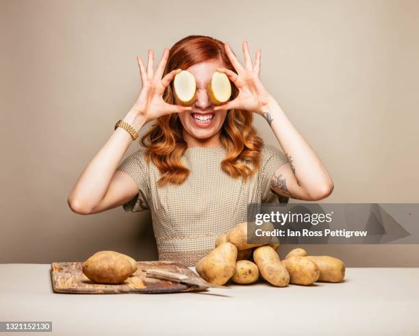 funny young woman with potatoes over her eyes - funny vegetable stockfoto's en -beelden